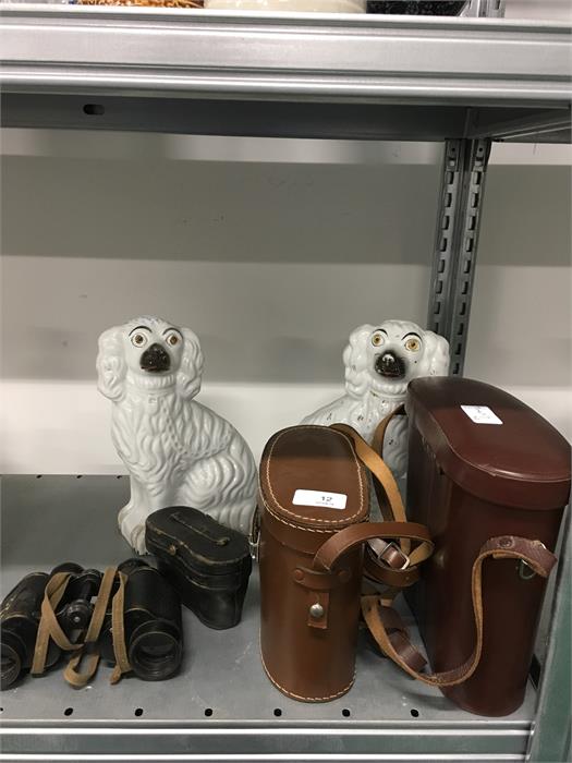 Four pairs of binoculars with two Staffordshire flat back dogs.