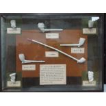 A quantity of clay pipes in black frame.