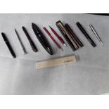 A tub containing pens and pencils, three early de la rue fountain pens, vintage Parker pen and