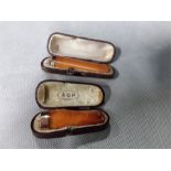 Two 9ct mounted cigar holders with amber mouth piece, cased.