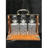 An oak Tantalus with three glass bottles.