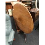 An antique oak circular tilt top table on tripod legs.