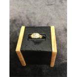 A small gold signet ring with inset white stone.