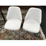 Two white leather 1970s style chairs.