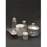 A silver brush together with a quantity of silver topped glass bottles.