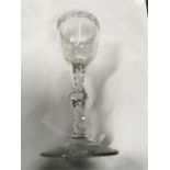 An 18th century wine glass with engraved bowl and facet cut stem and knop. (Two small chips to