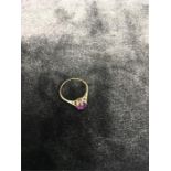 A gold ring with purple stone.