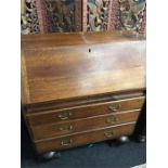 An oak bureau. fitted draws resting on ball feet