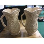 A pair of cream coloured jugs, embossed with flowers (9 inches high).