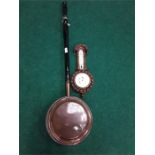 A copper bed pan with a wooden barometer.