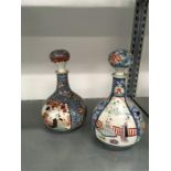 A pair of Japanese Imari design gugglets and stoppers decorated with garden scenes.