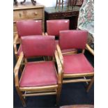 A set of four oak framed chairs with red leather seats.