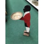 A carved wooden model of a waiter holding a tray.