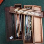 A quantity of knitting needles in wooden boxes.