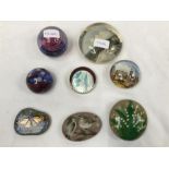 Eight paperweights with various designs.