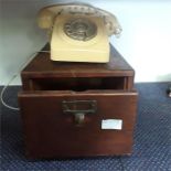 A wooden filing drawer together with a vintage telephone.