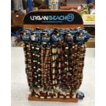 A wooden display stand with approximately fifty Urban Beach necklaces.
