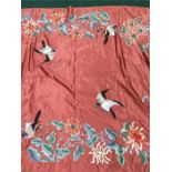 A Chinese coral pink coloured silk panel embroidered with birds and flowers.