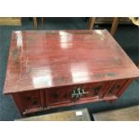 A red painted oriental style coffee table with inlaid decoration.