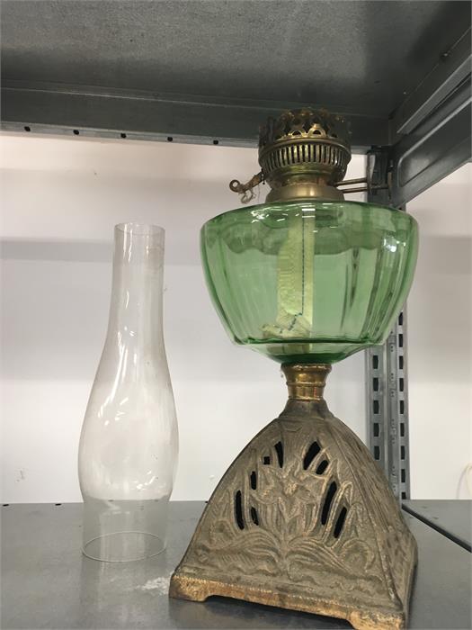 An oil lamp on a brass base with green glass reservoir and funnel.