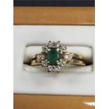 An 18ct gold ring set with central emerald surrounded by diamonds