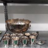 A silver plated punch bowl with ladle and nine cups.