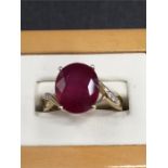 A large ruby ring set in 10ct gold with open shoulders set with diamond chips.