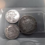 Three silver coloured medallions.