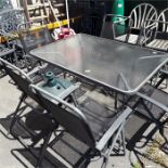 A glass topped garden table with six chairs.