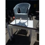 A white painted table with two wicker chairs.