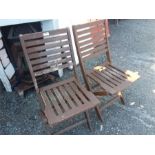 A pair of teak folding chairs.