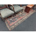 An antique woven Persian carpet in worn condition.