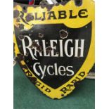 A yellow sheild shaped enamel sign “Raleigh Cycles”.