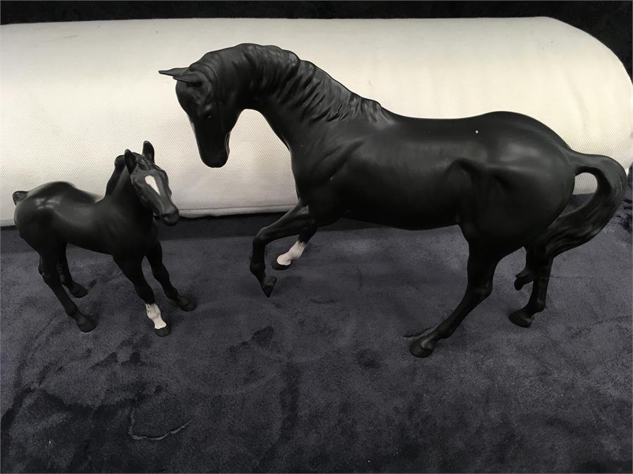 A model a black mare and foal with white blaze.