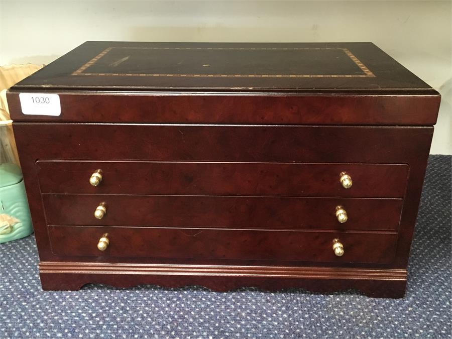 A large lift top wooden jewellery box with three drawers.