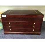 A large lift top wooden jewellery box with three drawers.