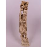 A Japanese carved ivory figurine of a sage holding a vase of flowers, with a bird perched in the