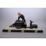 An Art Deco style spelter figure of a seated lady and deer mounted on an alabaster and onyx base,