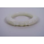 A Chinese carved white jade bangle with dragon head decoration, 3" diameter