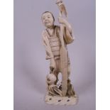 A Japanese carved ivory figurine of a fisherman standing with an oar, fish, octopus and bag of fish,