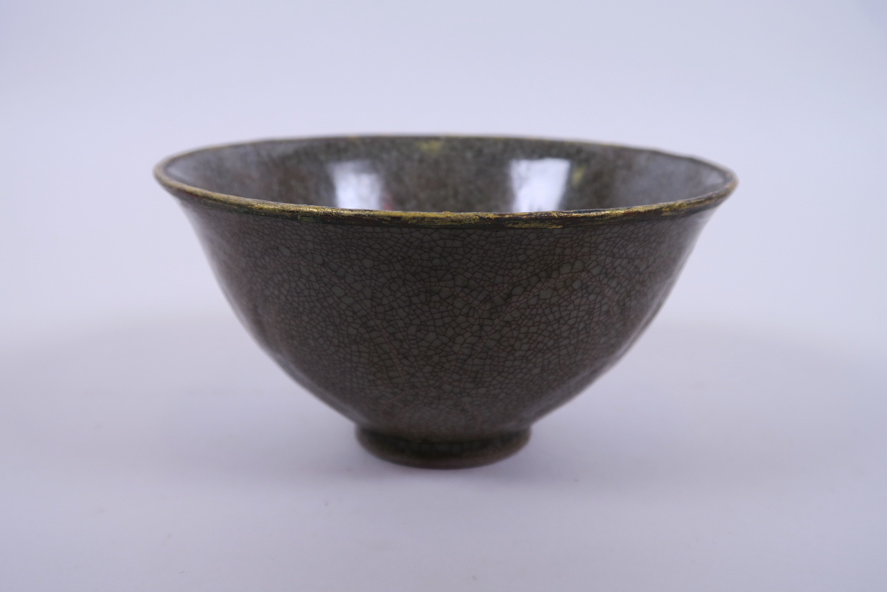 A Chinese celadon crackleware rice bowl with incised floral decoration and a gilt metal rim, 6"