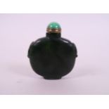 A Chinese spinach hardstone snuff bottle with carved mask decoration to shoulders, 2½" high