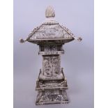 A Japanese carved ivory shrine in the form of a pagoda, the doors opening to reveal figures around a