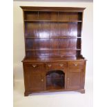 A Georgian pine and elm topped dresser, with panelled back Delft rack above three drawers and two