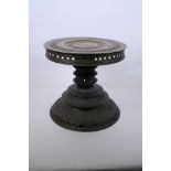 An Indian bronze lamp table with raised scrolling decoration, 10" high x 10½"