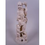 A Japanese carved marine ivory figurine of a man and child, the man with a bird climbing his robes