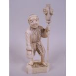 A Japanese carved marine ivory figurine of a traveller, 4½" high