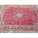 A large Persian Heriz carpet with traditional floral medallion design on a red field, 156" x 108"
