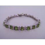 A silver, cubic zirconia and peridot set tennis bracelet, 7" long