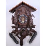 A Black Forest carved wood cuckoo clock decorated with carved figures of game etc., 16" x 12"